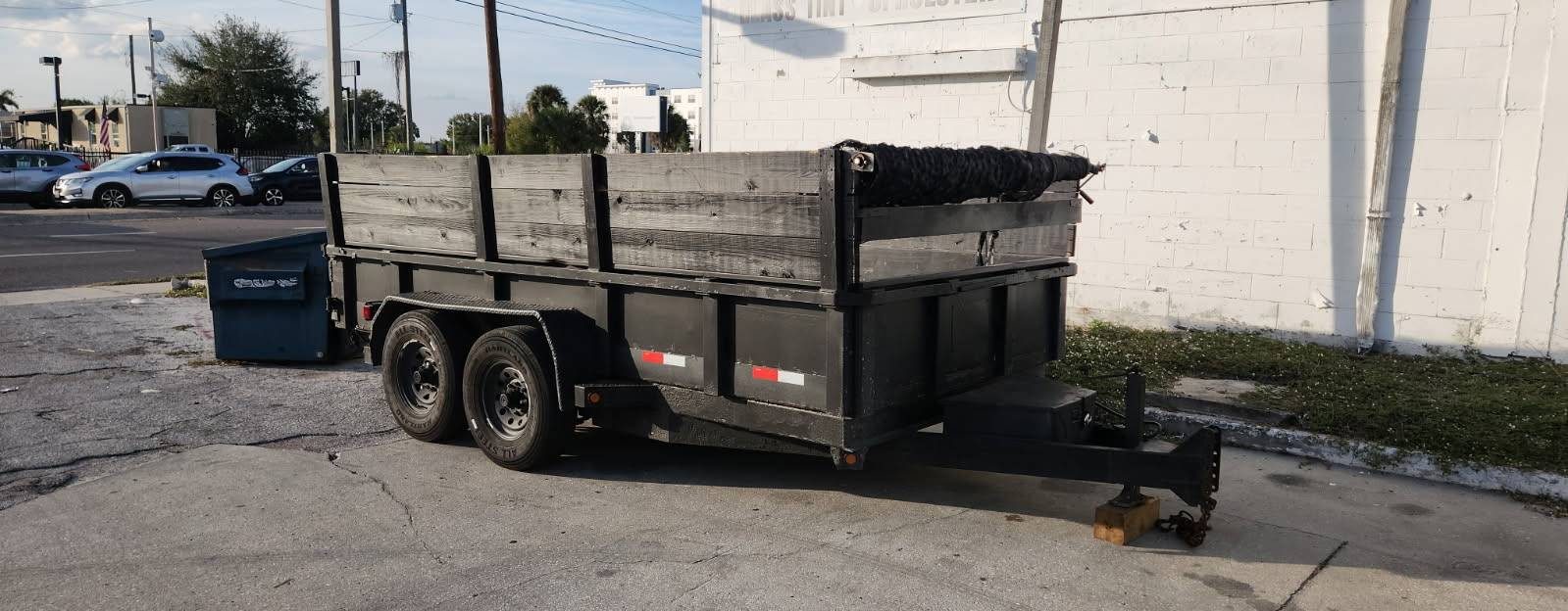 Black dump trailer parked at a Tampa concrete-block building