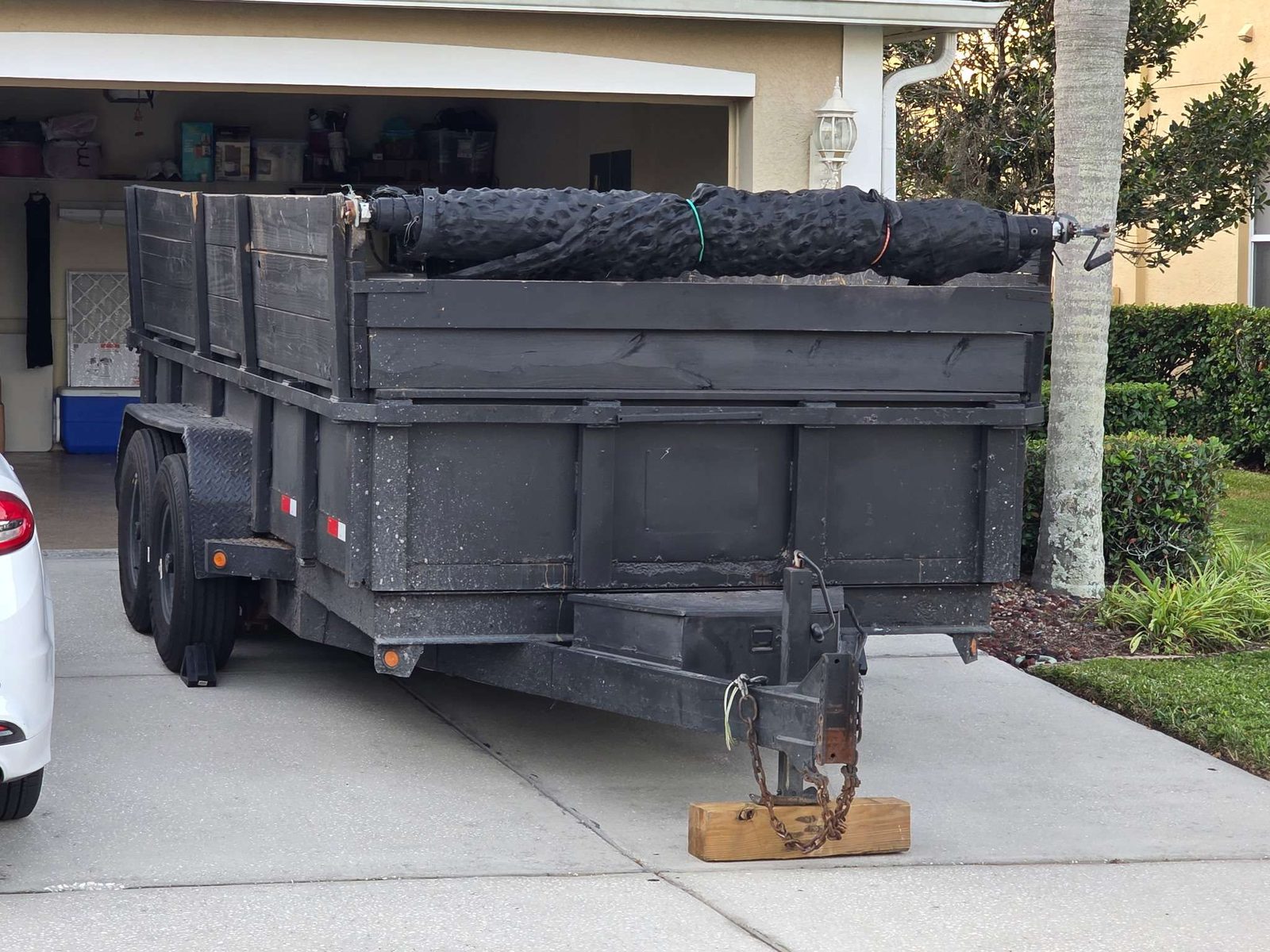 After: dump trailer staged in residential Tampa driveway, palm trees, ready for self-load or full-service haul